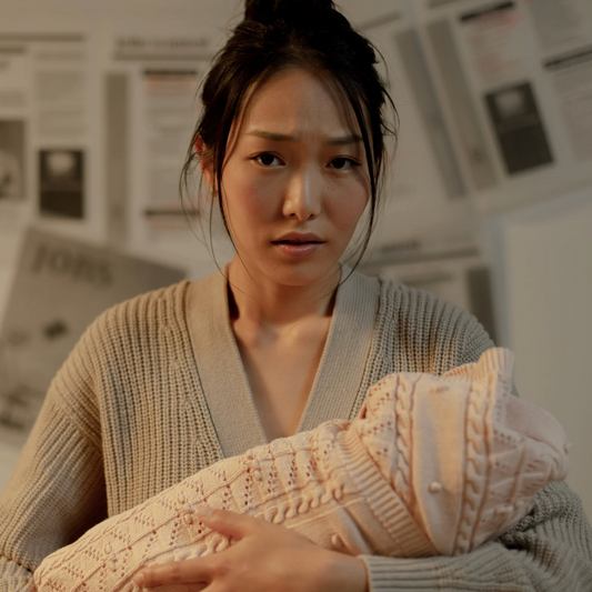 Jeune maman assise, fatiguée, dans son quotidien post-partum – illustration du sentiment de dépassement