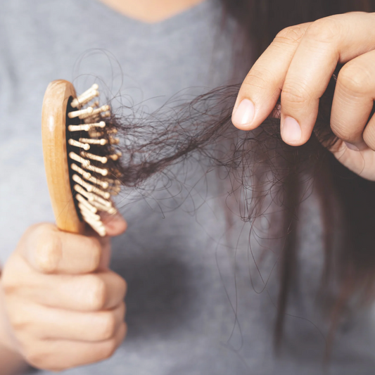 Jeune maman qui observe sa chute de cheveux post-partum – image représentative du baby hair et de la perte hormonale