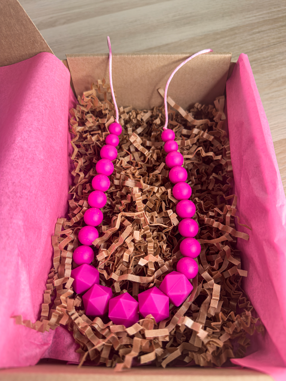 Collier d’allaitement en silicone fuchsia vif, captivant pour bébé et parfait pour maman.
