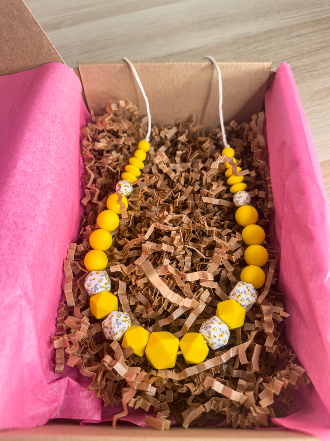 Collier d’allaitement lumineux en silicone jaune et motifs floraux, parfait pour l’éveil de bébé.