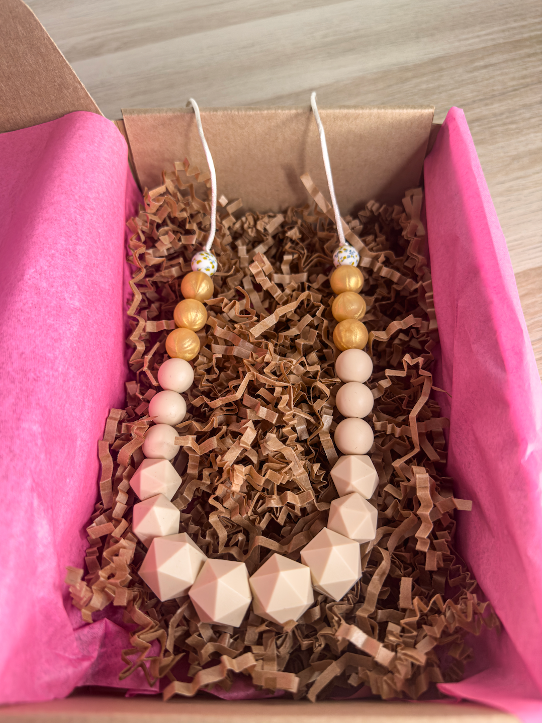 Collier d’allaitement chic avec des perles rose nude et dorées en silicone, idéal pour un look élégant et pratique.