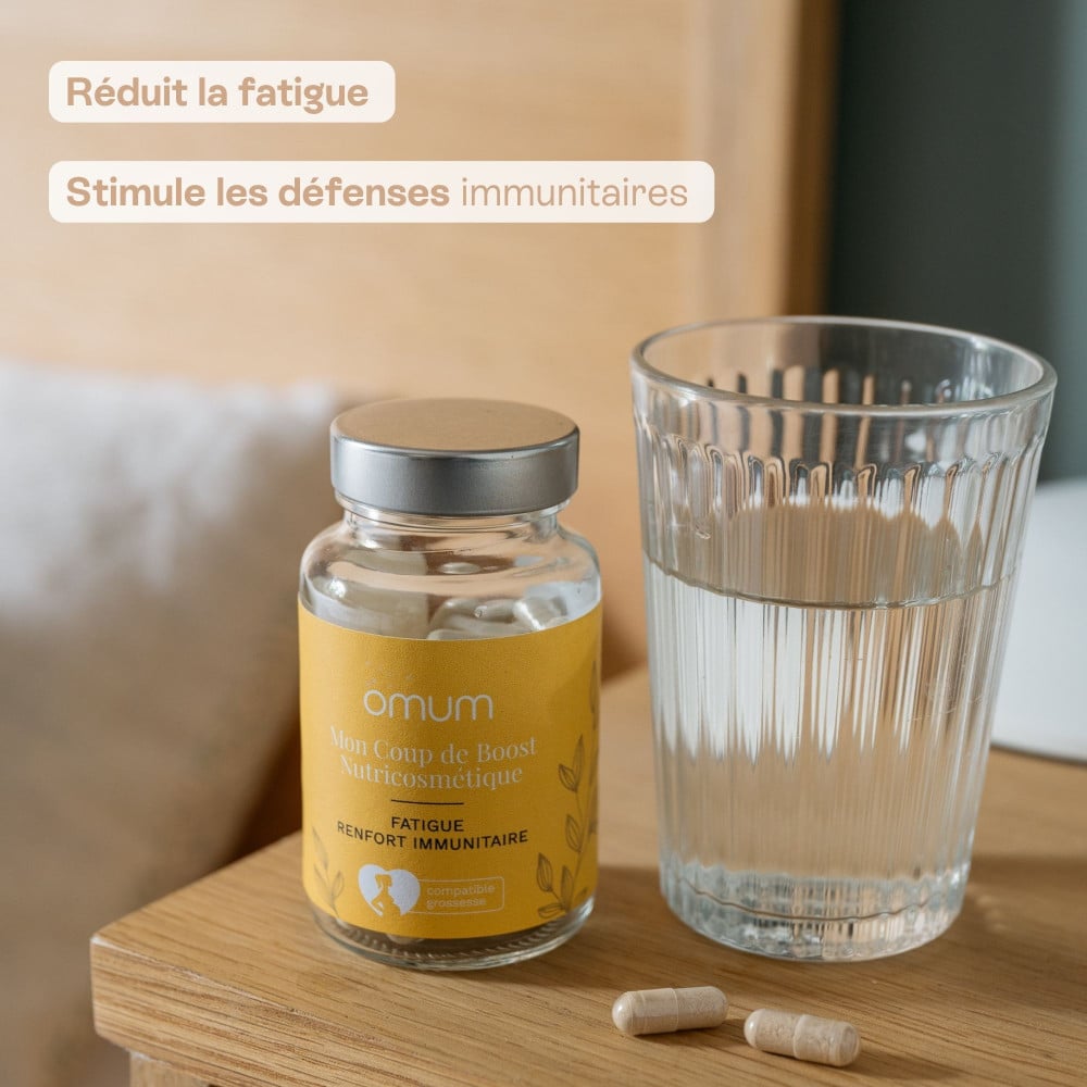 Pilulier Omum Mon Coup de Boost accompagné d’un verre d’eau, complément alimentaire pour réduire la fatigue et stimuler l’immunité.