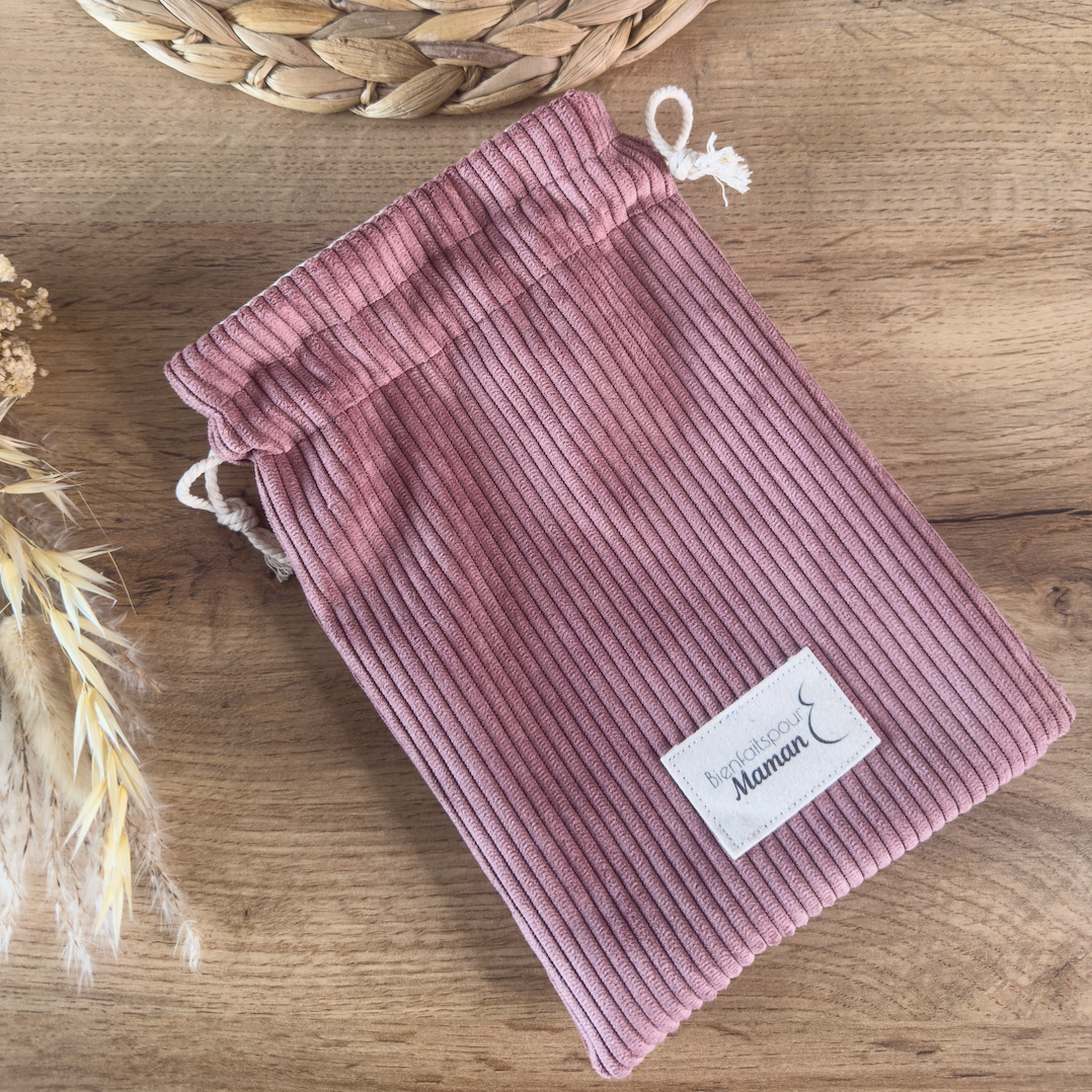 Pochon en velours rose ouvert laissant apparaître des produits de soin, idéal pour les cadeaux ou le rangement des essentiels bébé.
