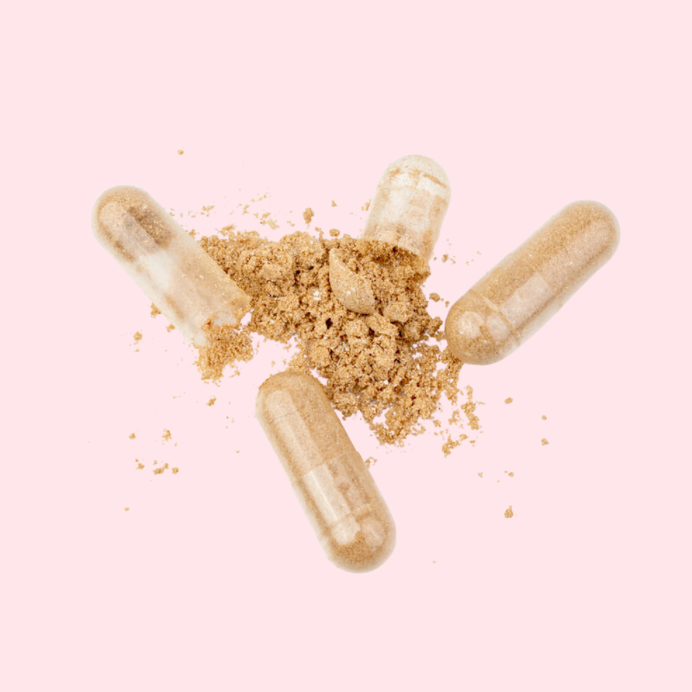 Gros plan sur les capsules du Complément Alimentaire Cheveux Forts avec du contenu en poudre autour.