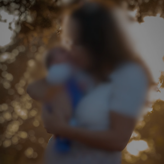 Maman souriante qui prend son bébé dans les bras – illustrant la culpabilité maternelle et l’importance de se faire confiance plutôt que de se juger mauvaise mère.