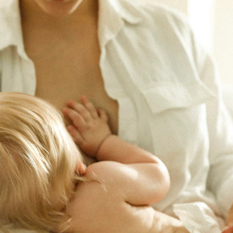 Maman tenant son bébé dans les bras pendant le mois de décembre, illustrant la charge mentale et la réalité des fêtes en famille.