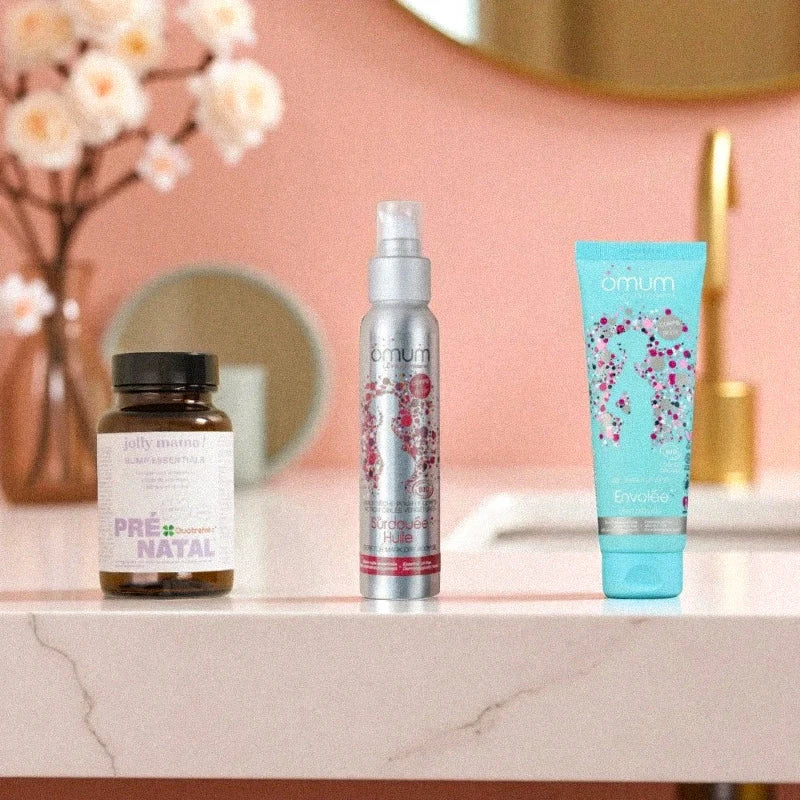 Trois soins maternité posés dans une salle de bain élégante aux tons roses et dorés, idéaux pour accompagner la grossesse en toute sécurité.