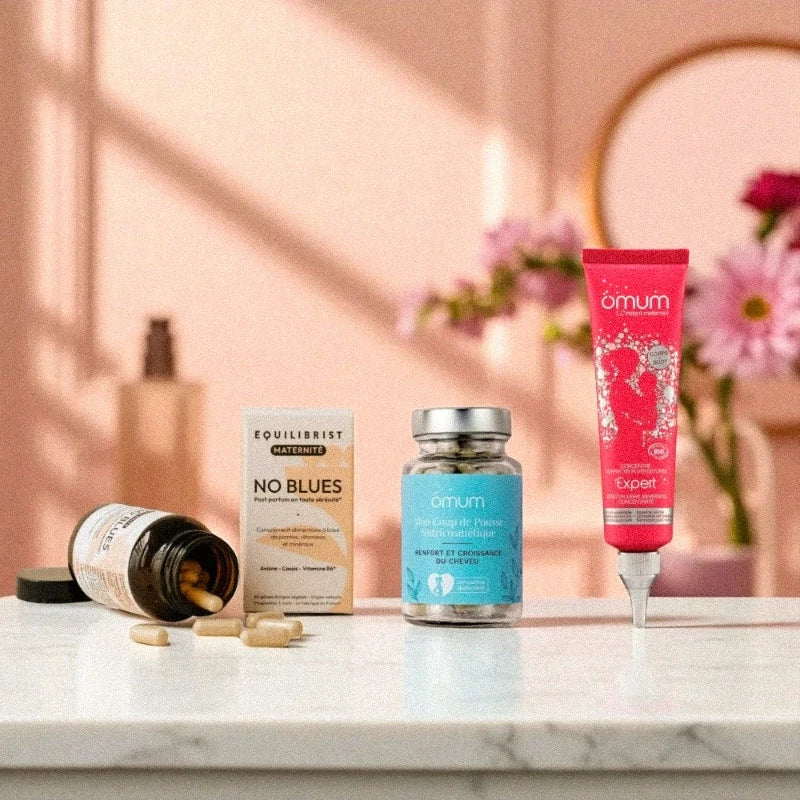 Trio de produits clean pour soutenir le post-partum, mis en scène dans une salle de bain lumineuse avec fleurs roses et détails dorés.