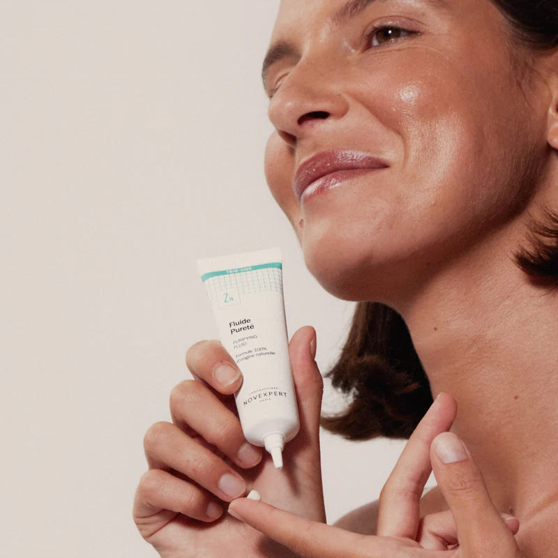 Femme souriante appliquant le Fluide Pureté Trio-Zinc Novexpert sur sa peau