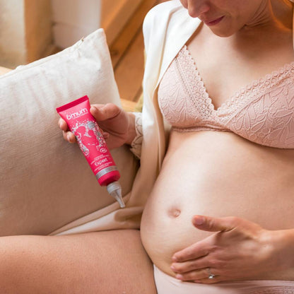 Femme enceinte assise appliquant la crème L’Expert sur son ventre pour prévenir et atténuer les vergetures.
