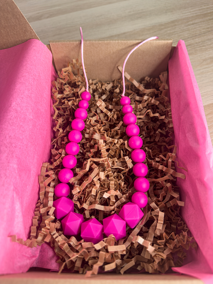 Collier d’allaitement en silicone fuchsia vif, captivant pour bébé et parfait pour maman.