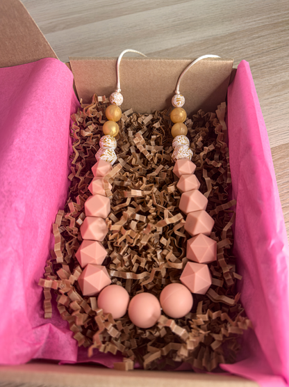 Collier d’allaitement avec des perles rose pêche et dorées en silicone, pour une touche glamour et sécurisée.