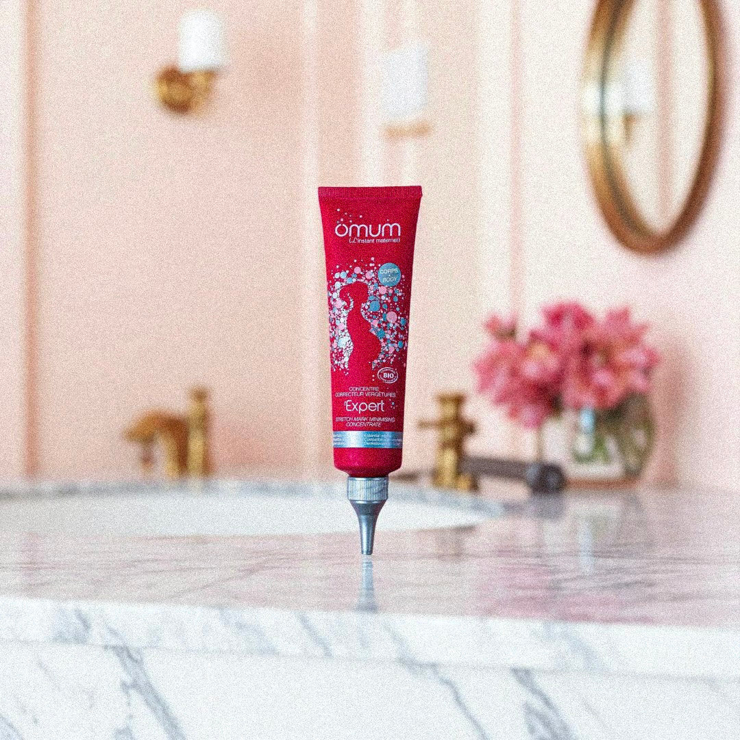 Tube de crème L’Expert Omum posé sur une table en marbre, soin correcteur naturel pour atténuer les vergetures récentes.