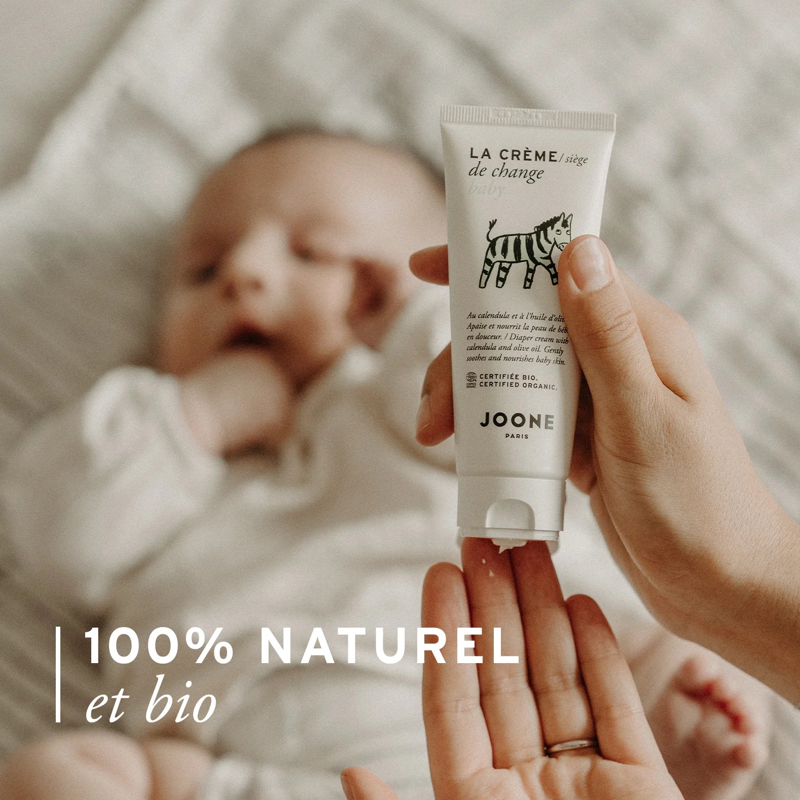 Parent tendant la crème de change bio Joone à un bébé, formule 100 % naturelle et bio.