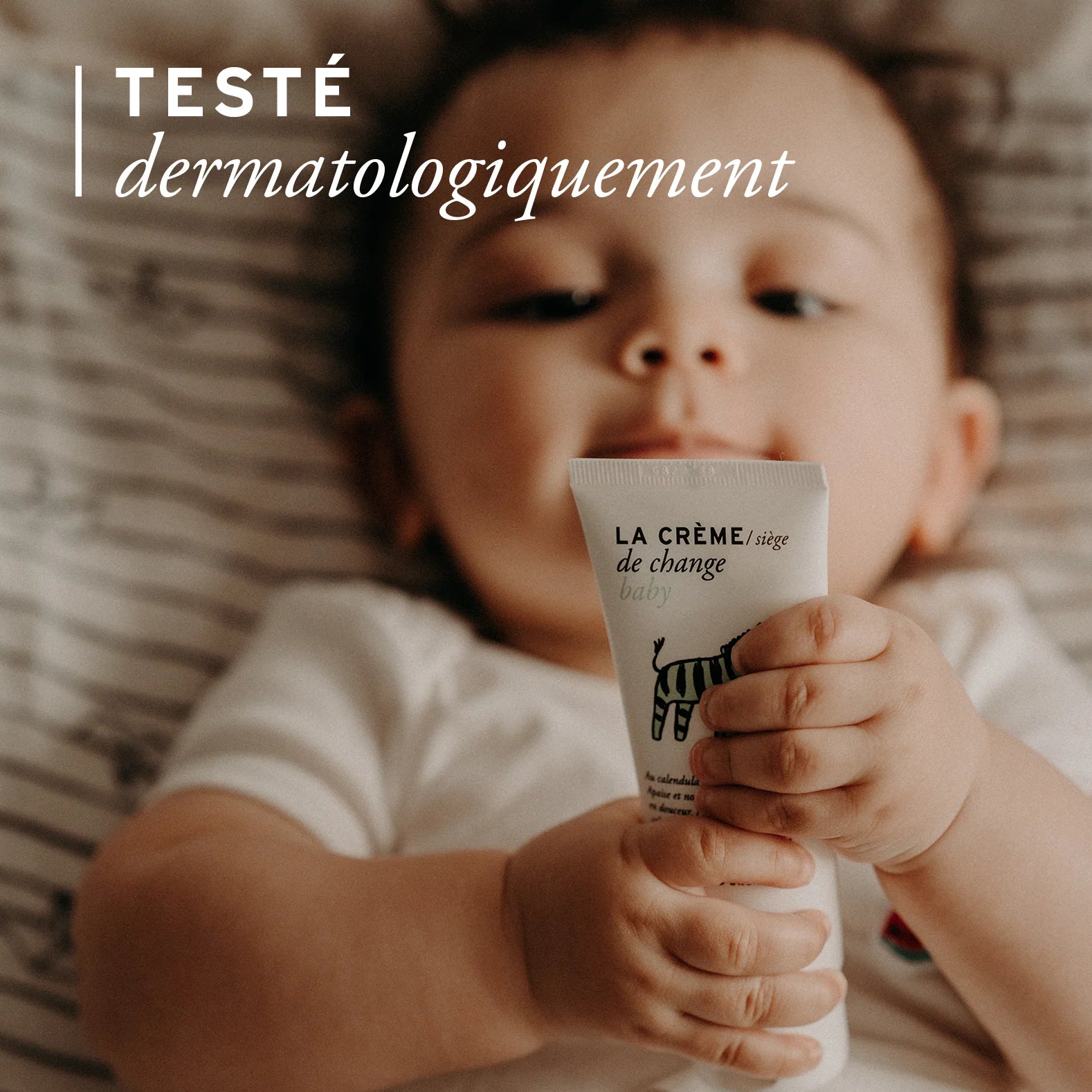 Bébé tenant la crème de change bio Joone, testée dermatologiquement.