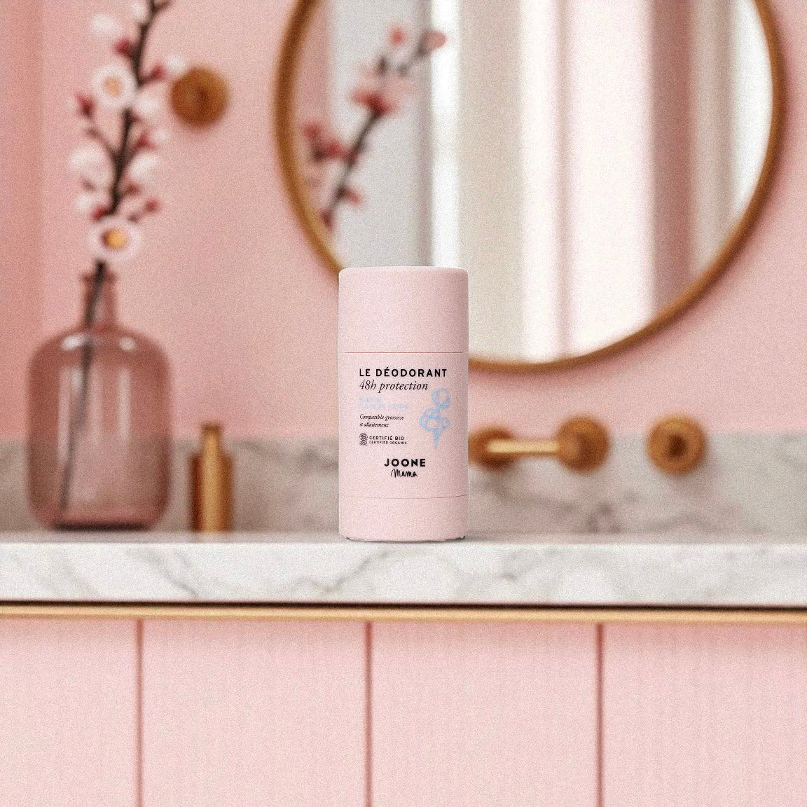 Déodorant bio Joone Fleur de Coton posé dans une salle de bain au décor rose poudré.