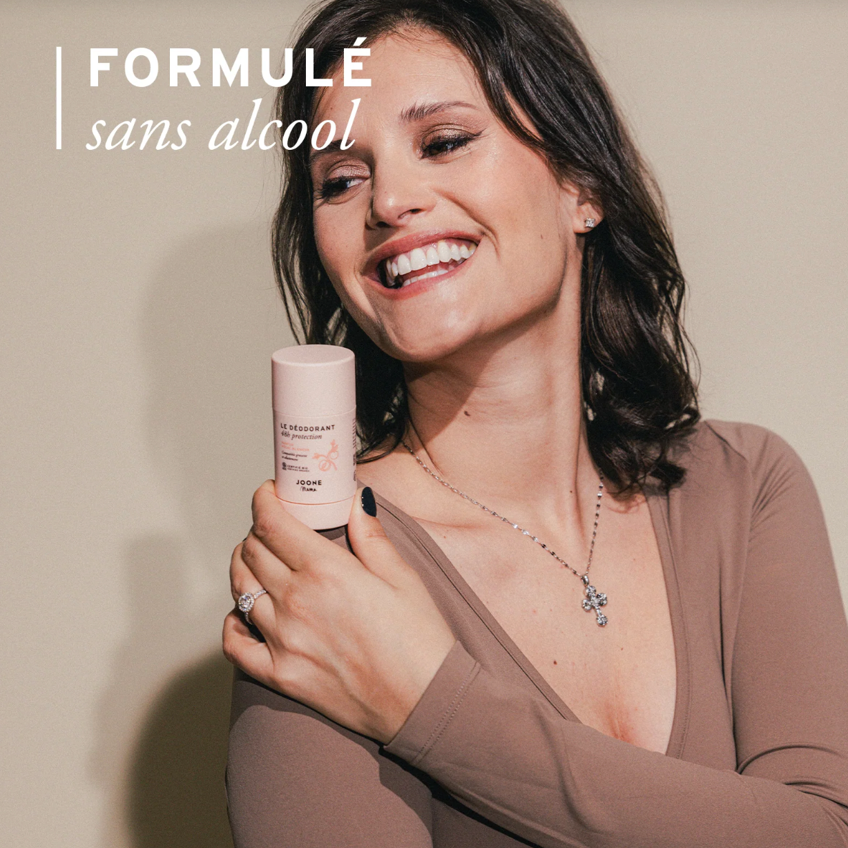 Femme enceinte souriante tenant le déodorant bio Joone Fleur de Coton.