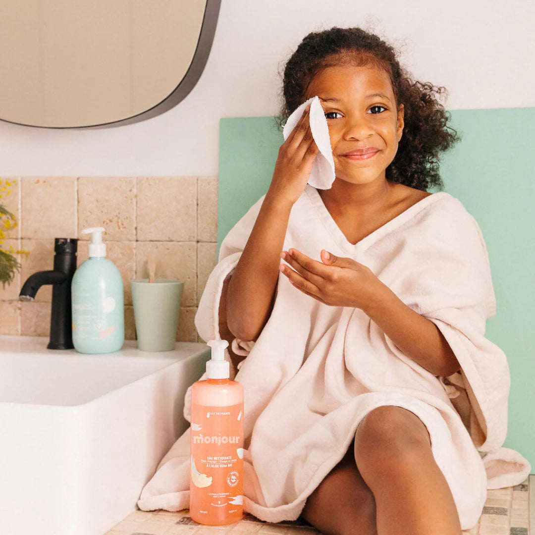 Enfant utilisant un coton pour appliquer l’eau nettoyante Monjour après le bain