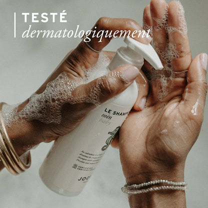 Mains savonneuses tenant le flacon de shampoing soin bio Joone, testé dermatologiquement.