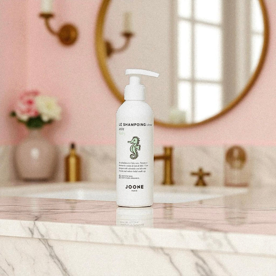Shampoing soin bio Joone pour bébé posé dans une salle de bain au décor rose poudré.