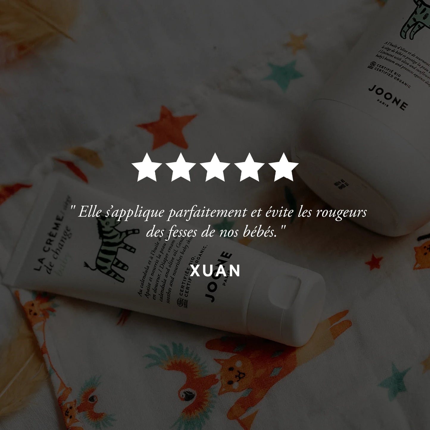 Avis client positif sur la crème de change bio Joone, produit posé sur un tissu imprimé.