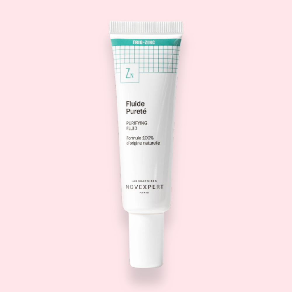 Fluide Pureté de Novexpert, soin purifiant non-comédogène, tube blanc sur fond rose.