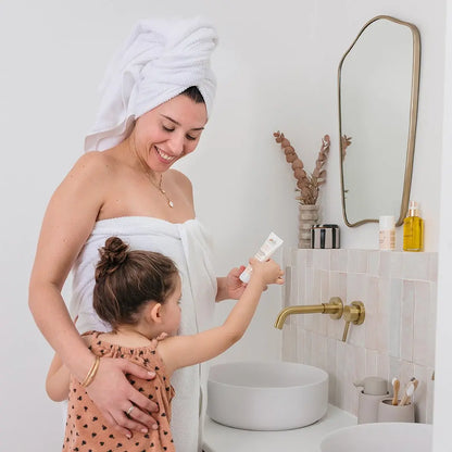 Maman appliquant crème solaire compatible grossesse et allaitement dans salle de bain